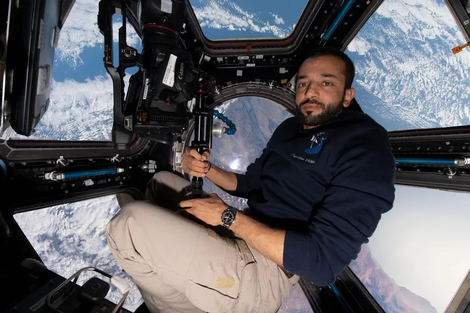 Astronauta na Cúpula da Estação Espacial olhando a Terra e o céu através das janelas