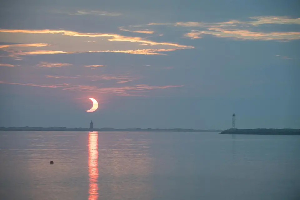 Eclipse solar parcial fotografado ao nascer do sol, com o Sol em forma de crescente