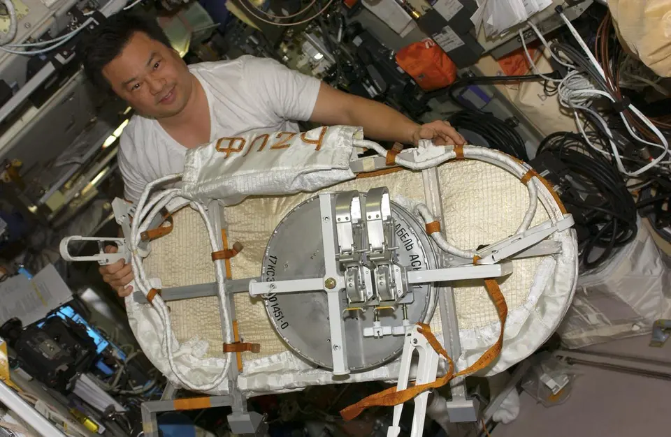 Astronauta segurando um receptor GPS dentro da Estação Espacial
