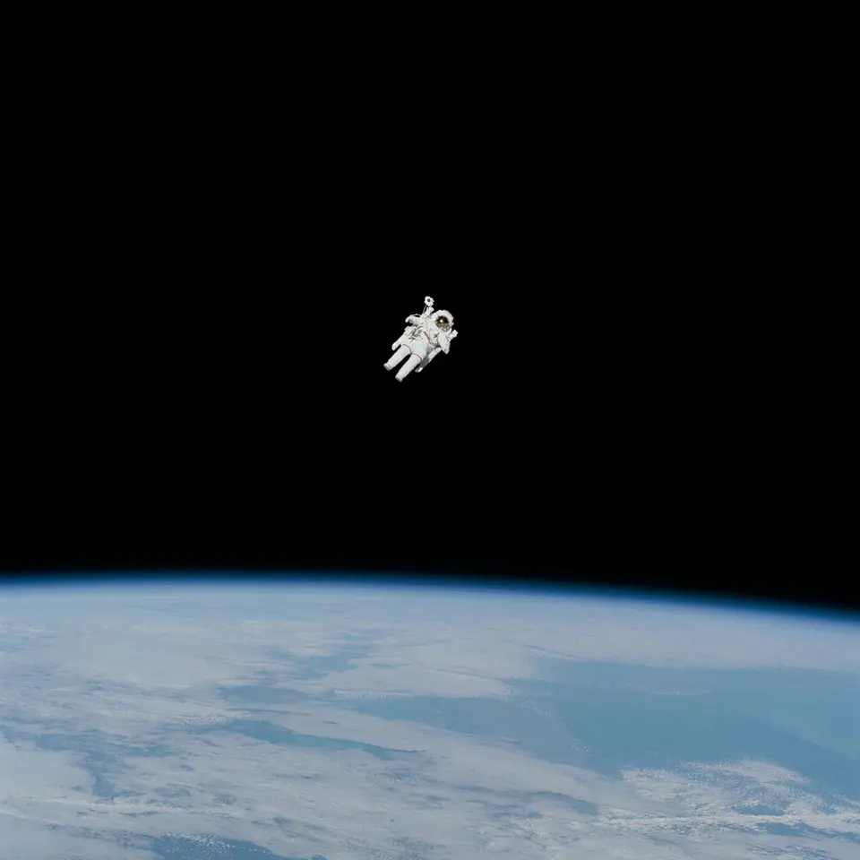 Bruce McCandless flutuando sozinho no espaço, sem nenhum cabo, com a Terra azul embaixo