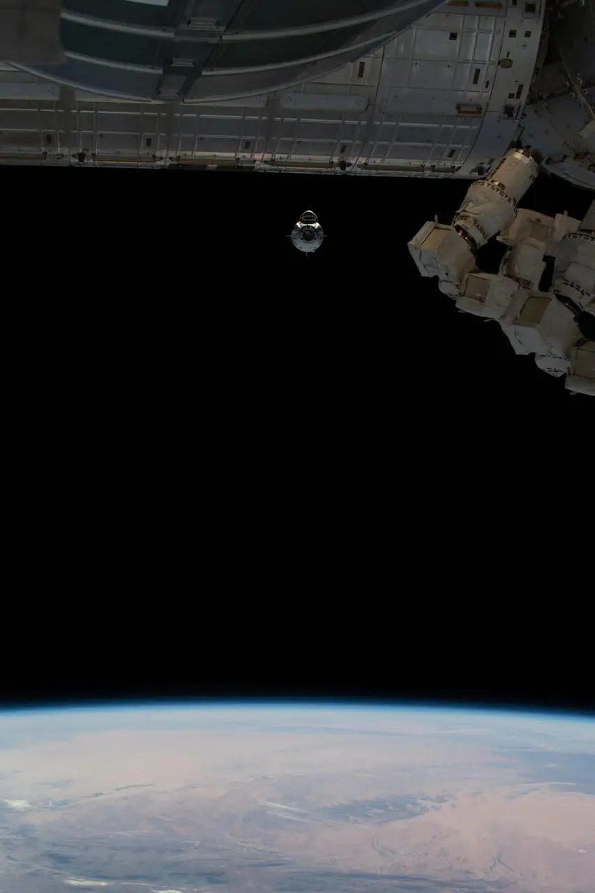 Cápsula Crew Dragon acoplada à Estação Espacial com a Terra ao fundo