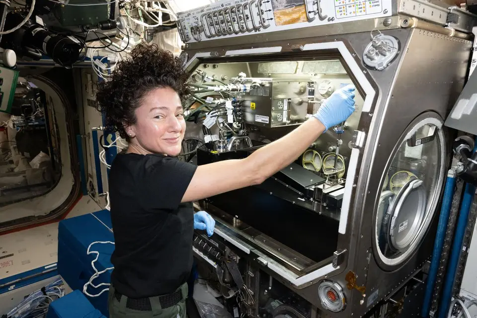 Astronauta configurando equipamento de pesquisa dentro da Estação Espacial Internacional